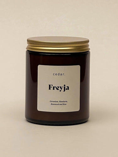 Candle in amber jar with the label freyja - geranium and mandain