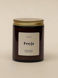 Candle in amber jar with the label freyja - geranium and mandain